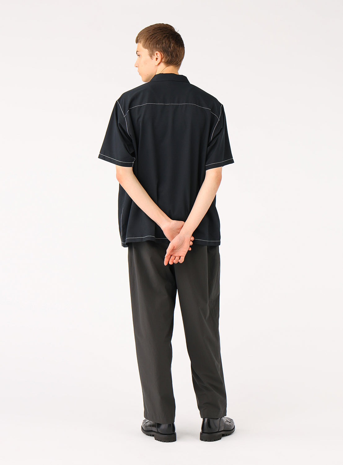 Back of a model wearing the black BEAMS Stitching Easy Shirt, highlighting the wide, relaxed silhouette and clean lines. 