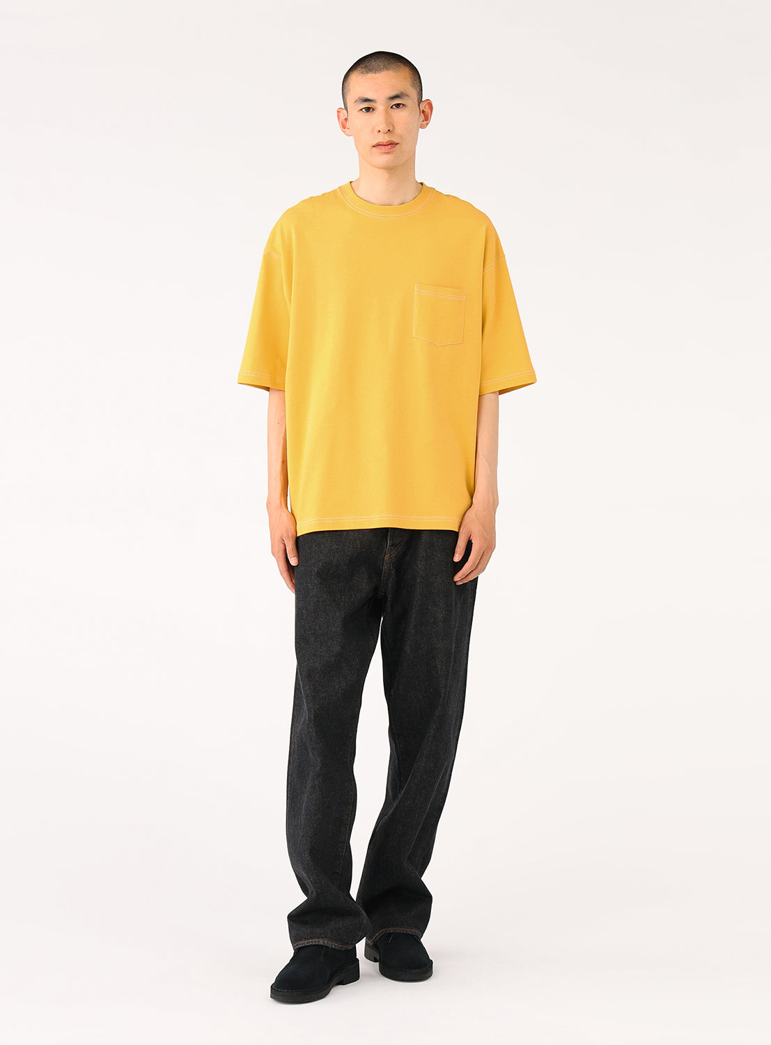 model wearing a yellow t-shirt, showing the full casual outfit with black pants.