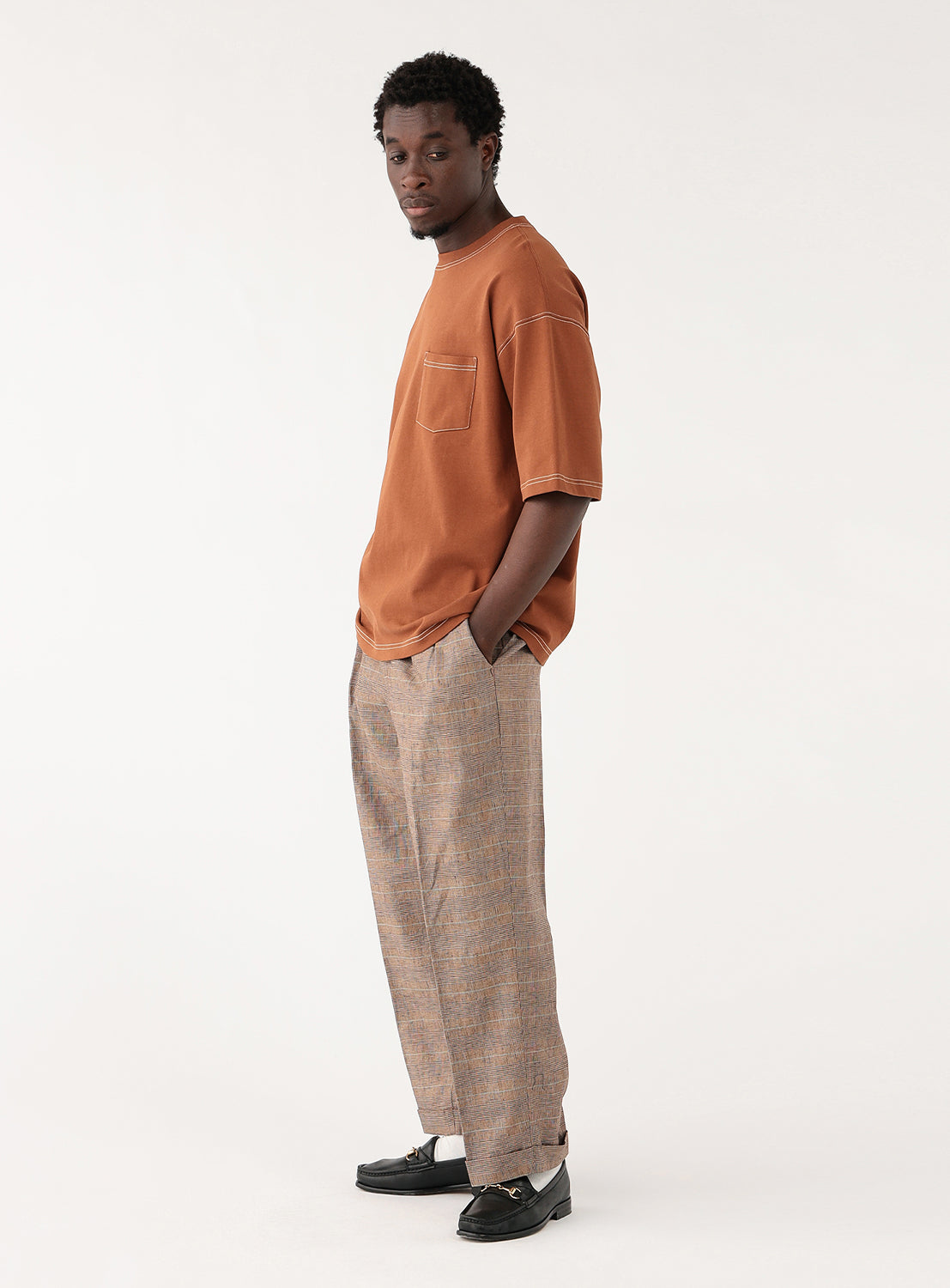 Side view of a model in the rust-colored t-shirt, highlighting the loose fit and drape of the sleeves.