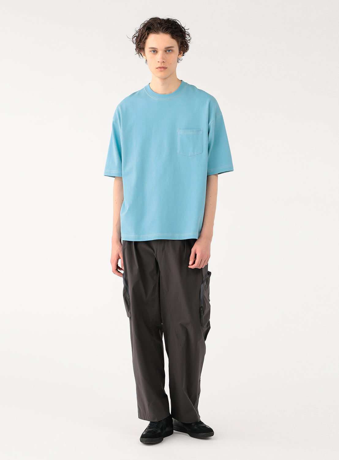 model wearing the light blue t-shirt, showcasing the full casual outfit with dark pants.