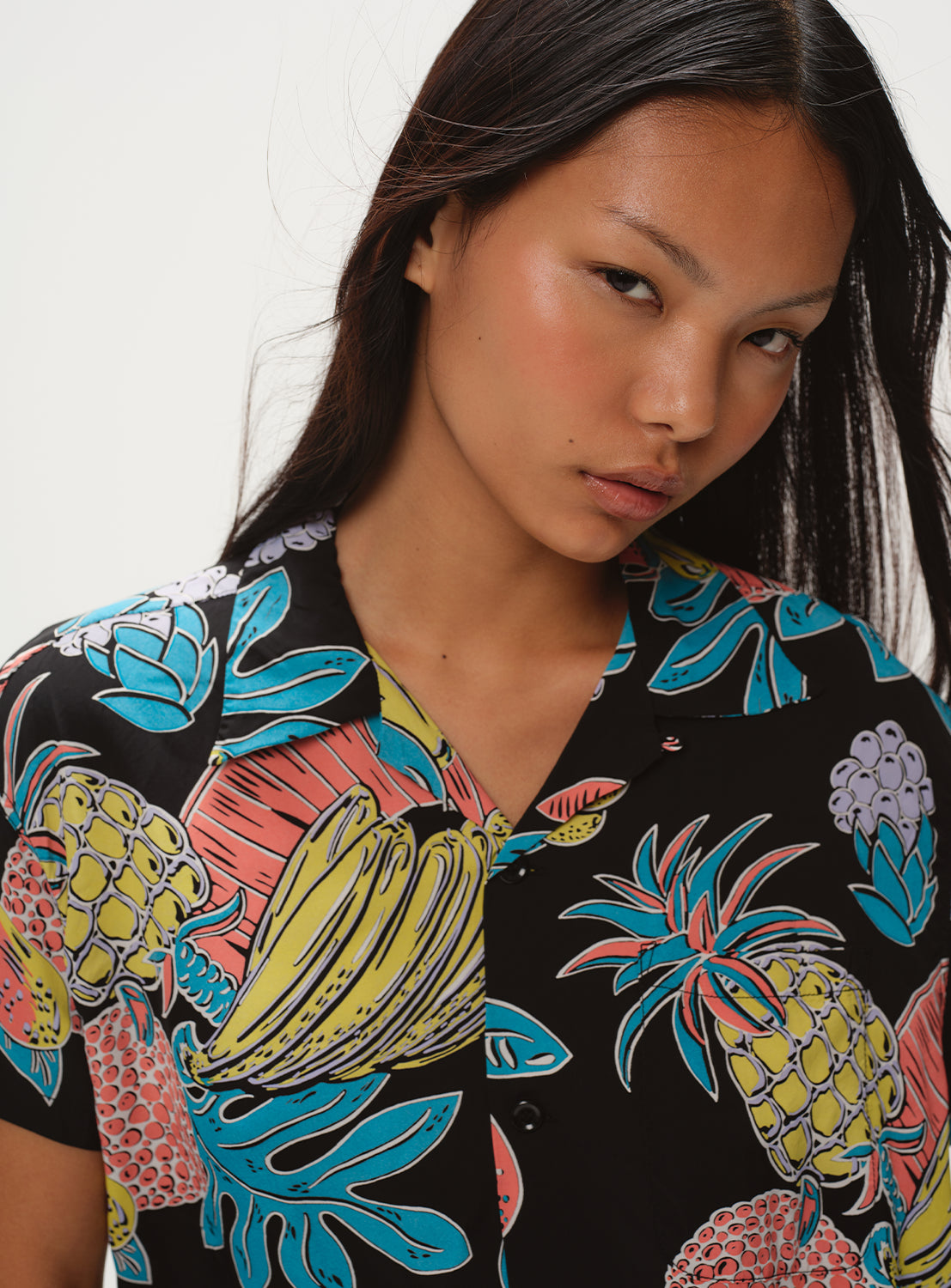 Close-up of a model wearing the black patterned dress, focusing on the collar and the colorful print.