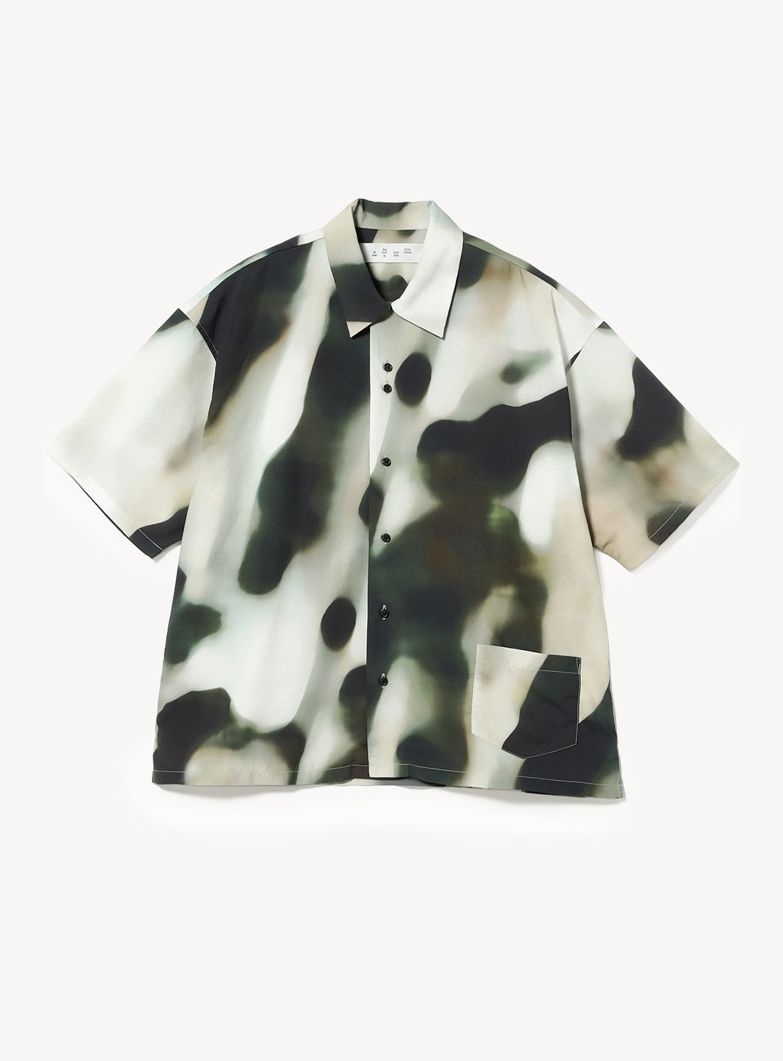 The BAL Blur Pattern Open-Collar Short-Sleeve Shirt features a loose fit and an abstract blurred camouflage design in green, black, beige, and white. Showcasing original textile artwork, this shirt is finished with an open collar and a front pocket on the lower right side.