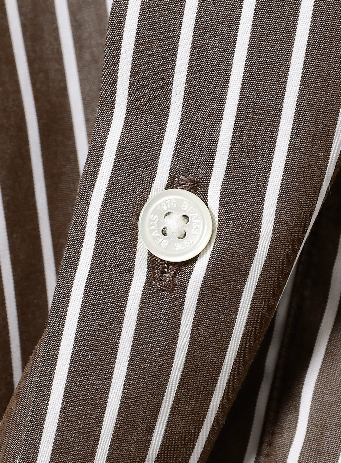 Close-up of white button on a brown and white striped fabric.