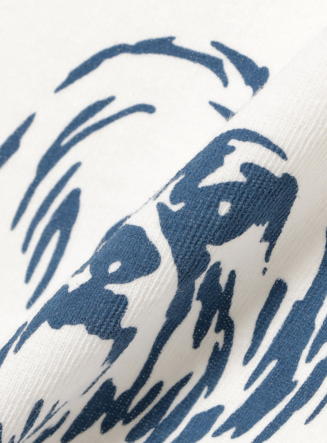 Close-up of white t-shirt fabric, detailing the blue abstract graphic print and textile texture.