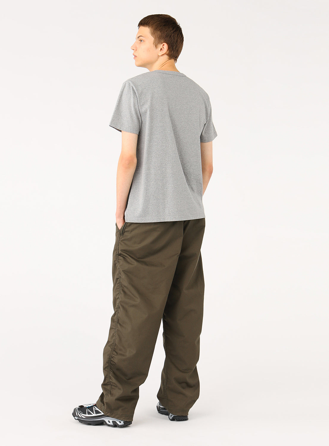 Model wearing a light grey t-shirt and olive green pants, back view, showcasing the plain back of the shirt.