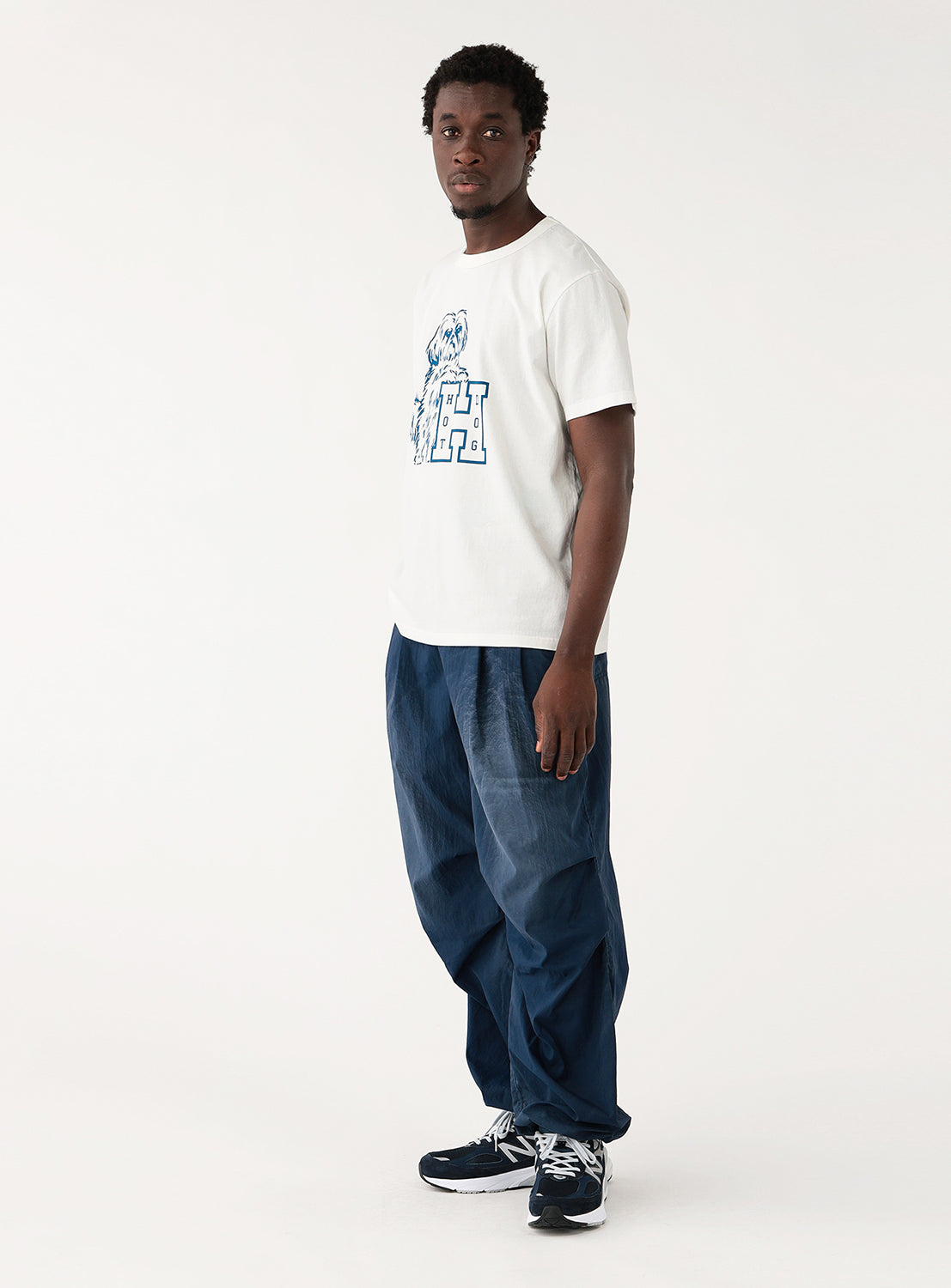 Model wearing a white t-shirt with a blue graphic and blue jeans, side view, emphasizing the shirt's drape.