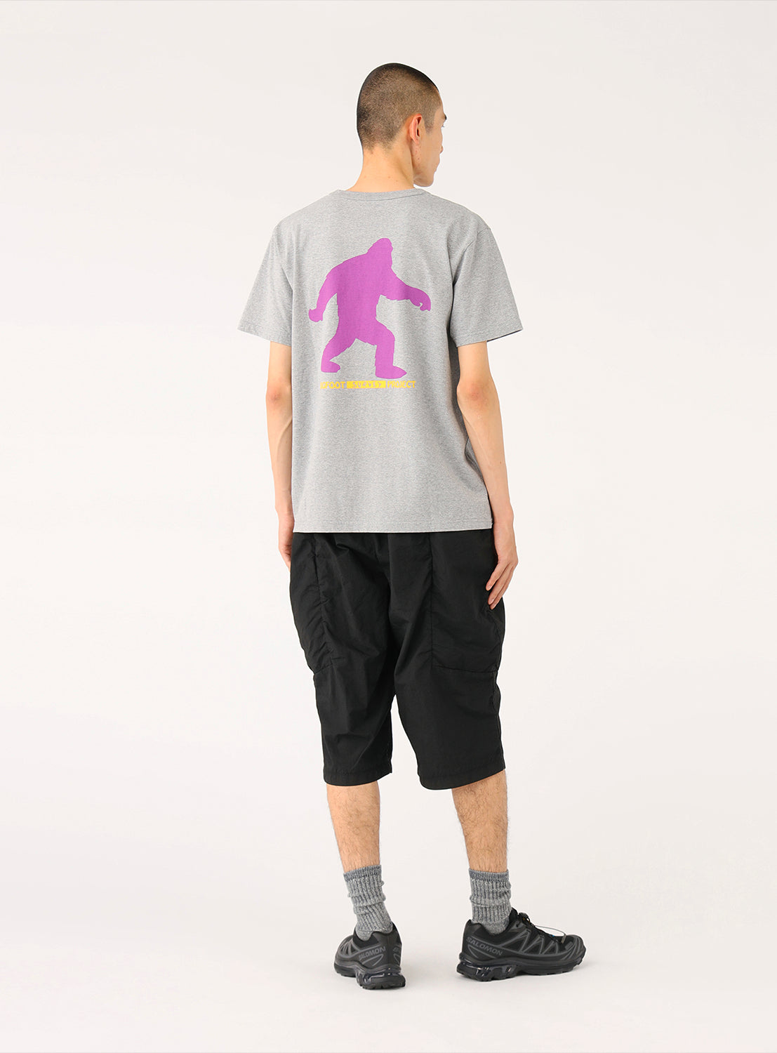 Back view of a model in black shorts, highlighting the clean silhouette and discreet utility.