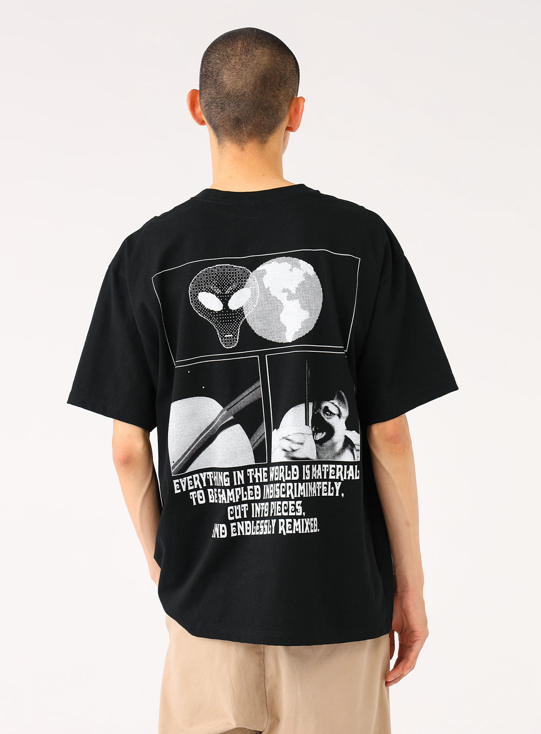 Model wearing a black t-shirt, back view, highlighting the white multi-panel abstract graphic design and text.