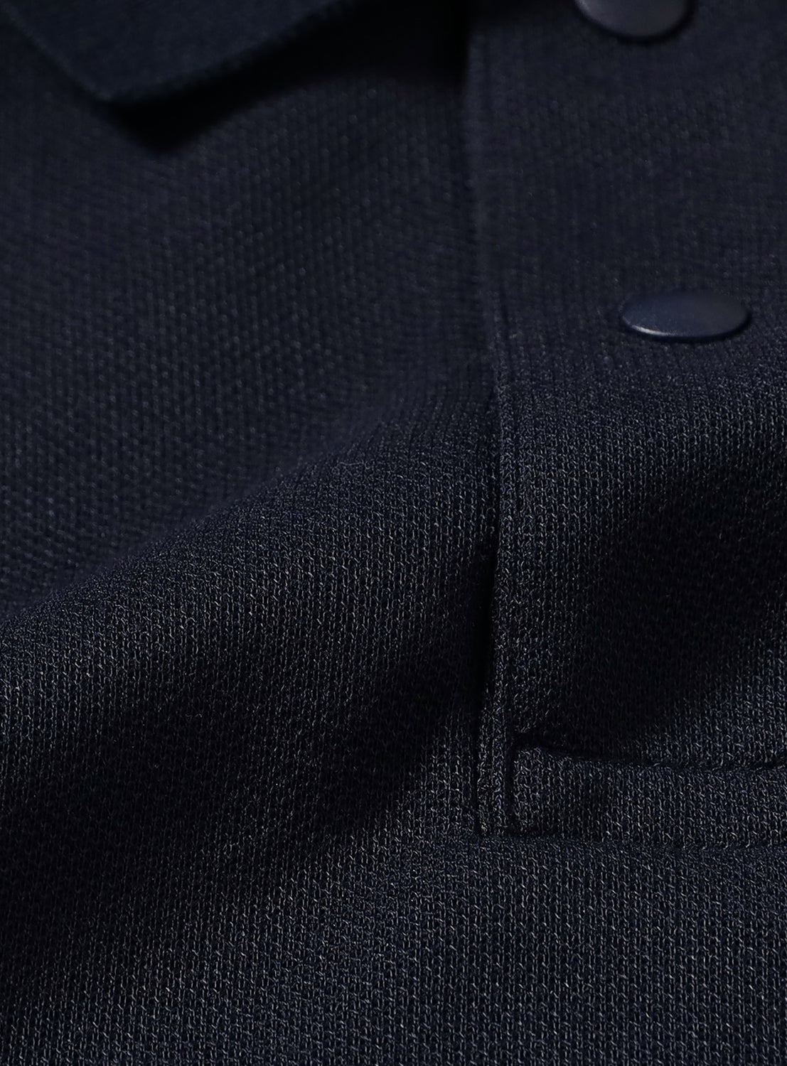 Close-up of a navy blue textured fabric with matching buttons.