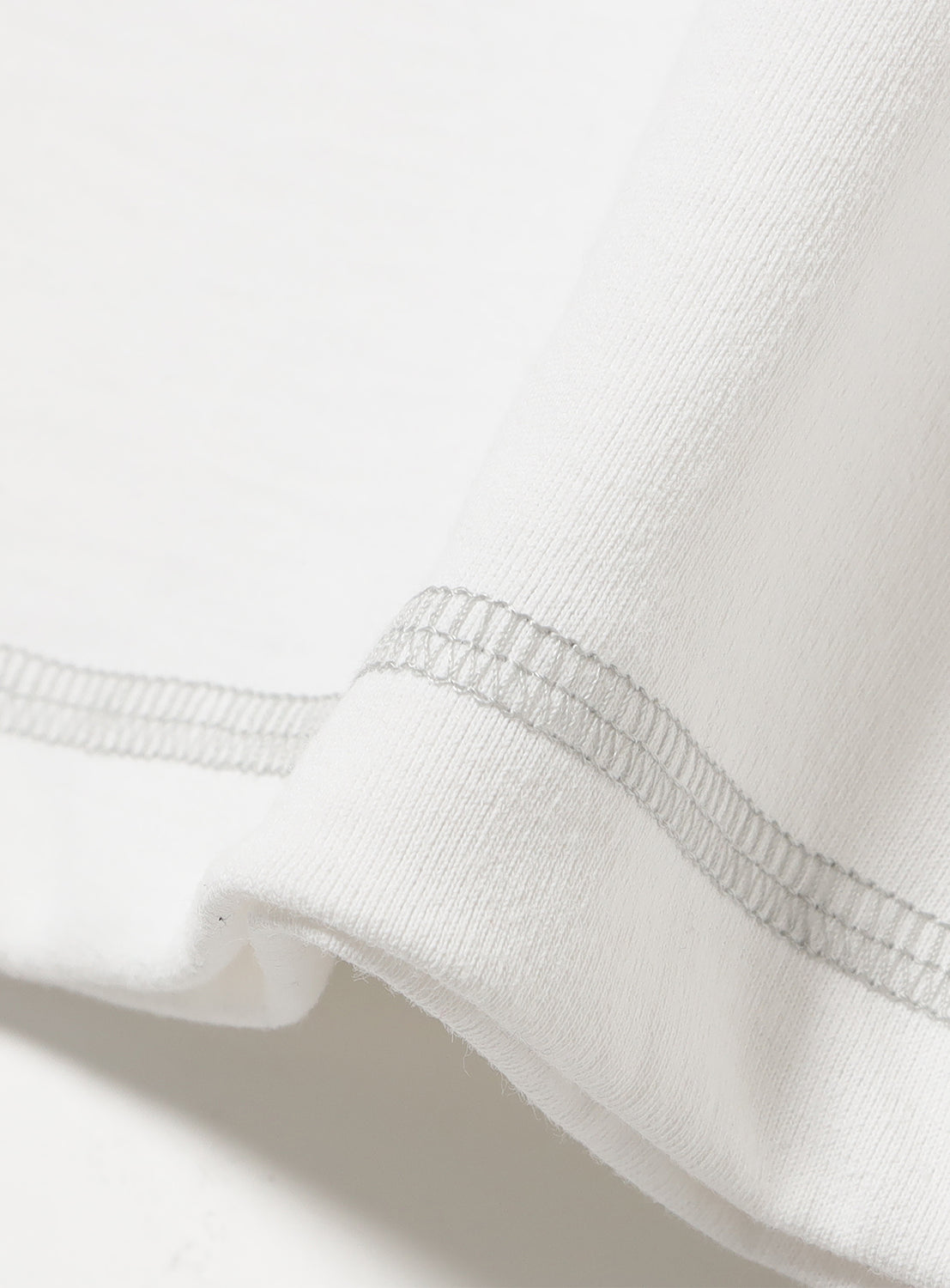 Close up of white t-shirt material and the matching stitching detail. 