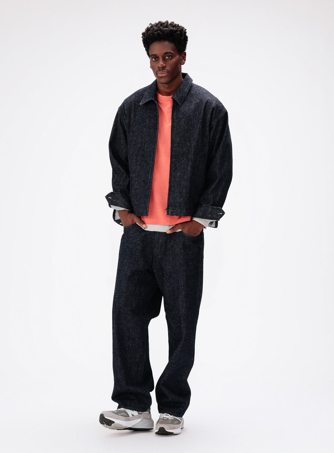 A person wearing a vintage-inspired dark denim jacket and matching BEAMS Wide Fit Denim Pants over a coral-colored t-shirt.
