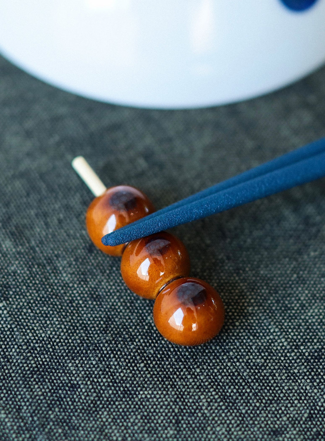 Chopstick rest on a dark fabric surface with a white plate in the background.