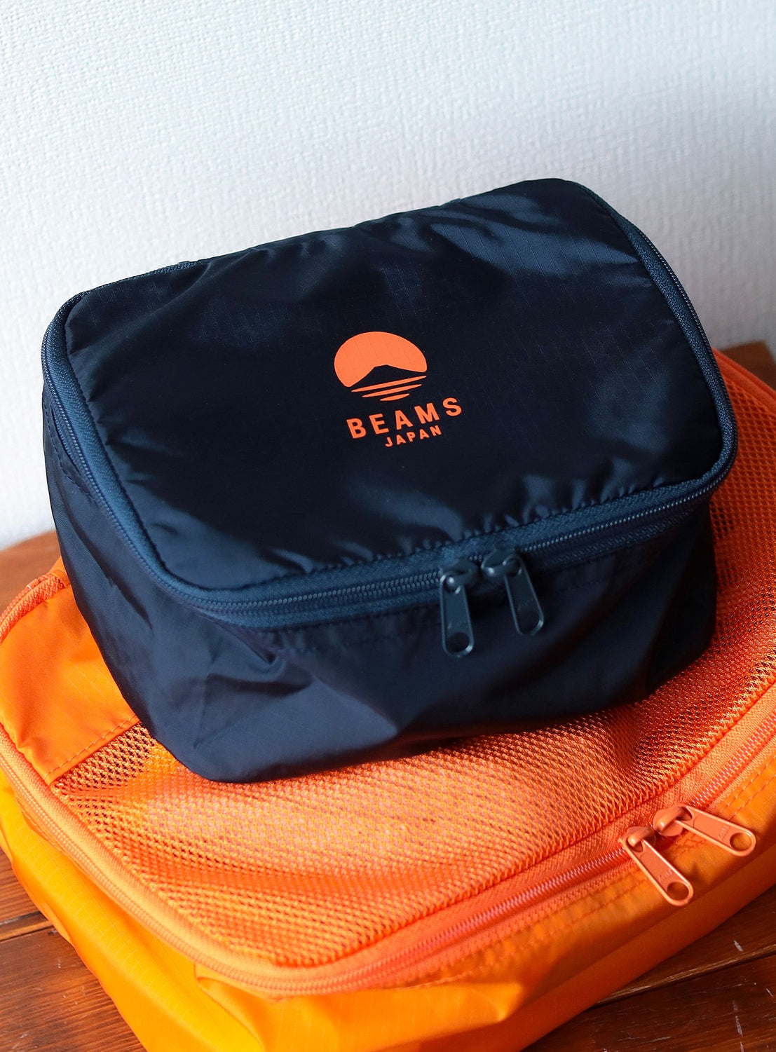 Black pouch with 'BEAMS' logo on top of an orange mesh bag.