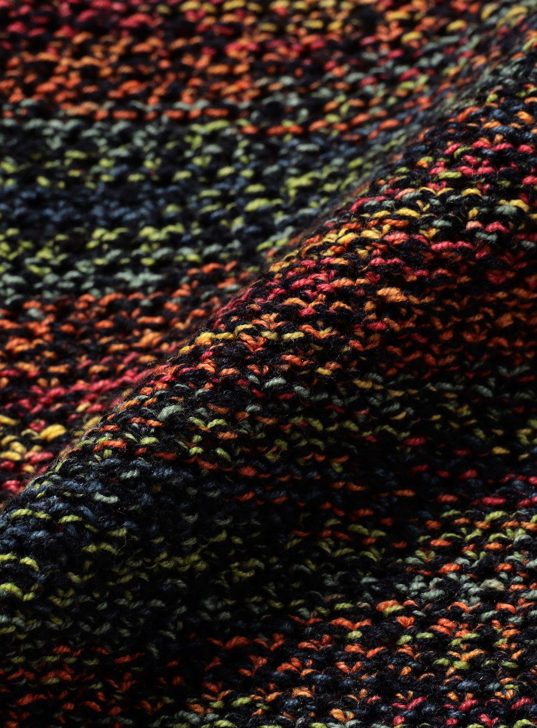 Close-up of a 7-Gauge Mesh Crew Neck Top in a gradient mesh knit fabric with a multicolored texture of red, orange, yellow, blue, and black yarn.