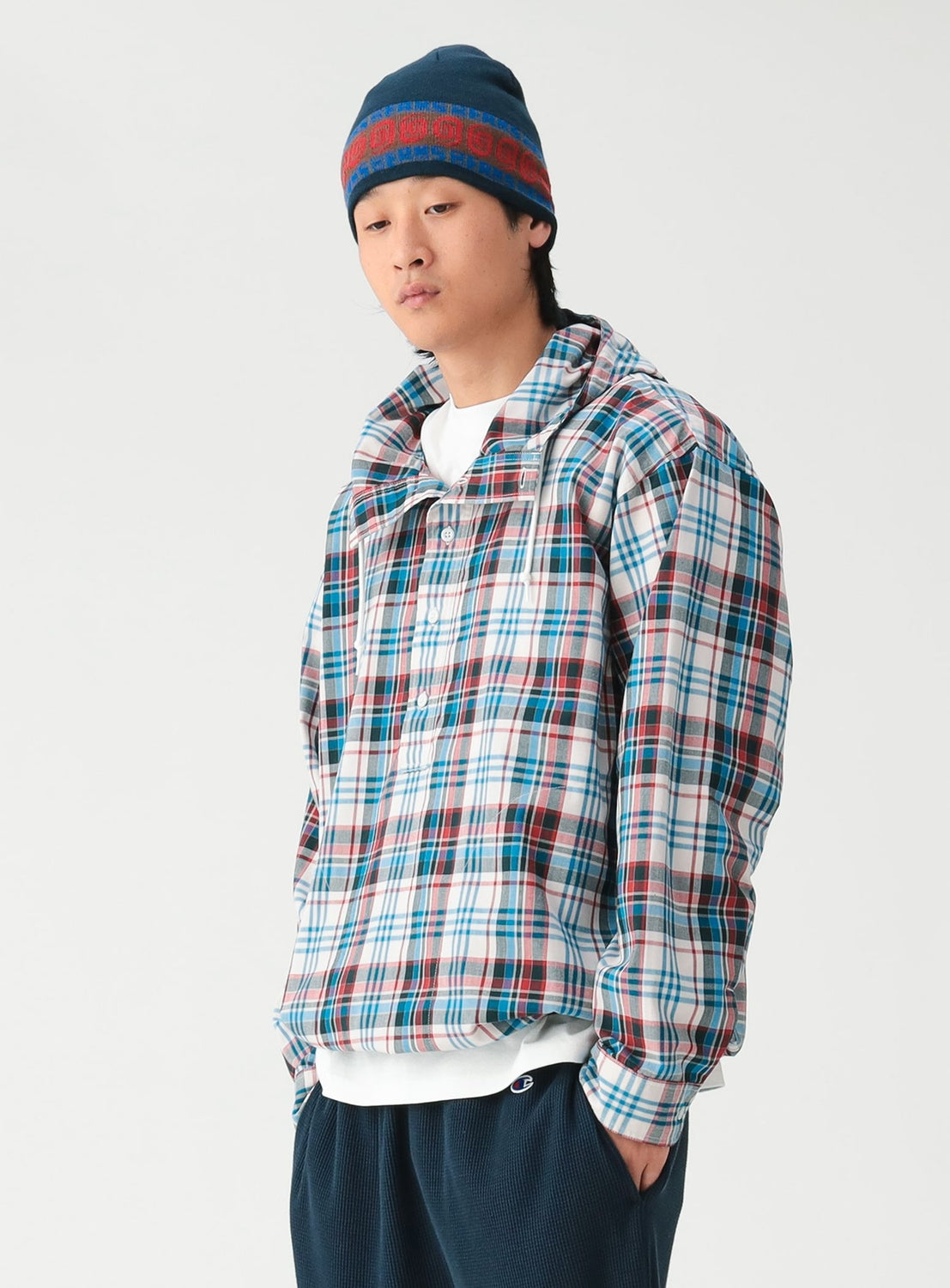 A person wearing a BEAMS Check Hooded Shirt in a white, blue, and red check pattern over a white t-shirt and dark pants.
