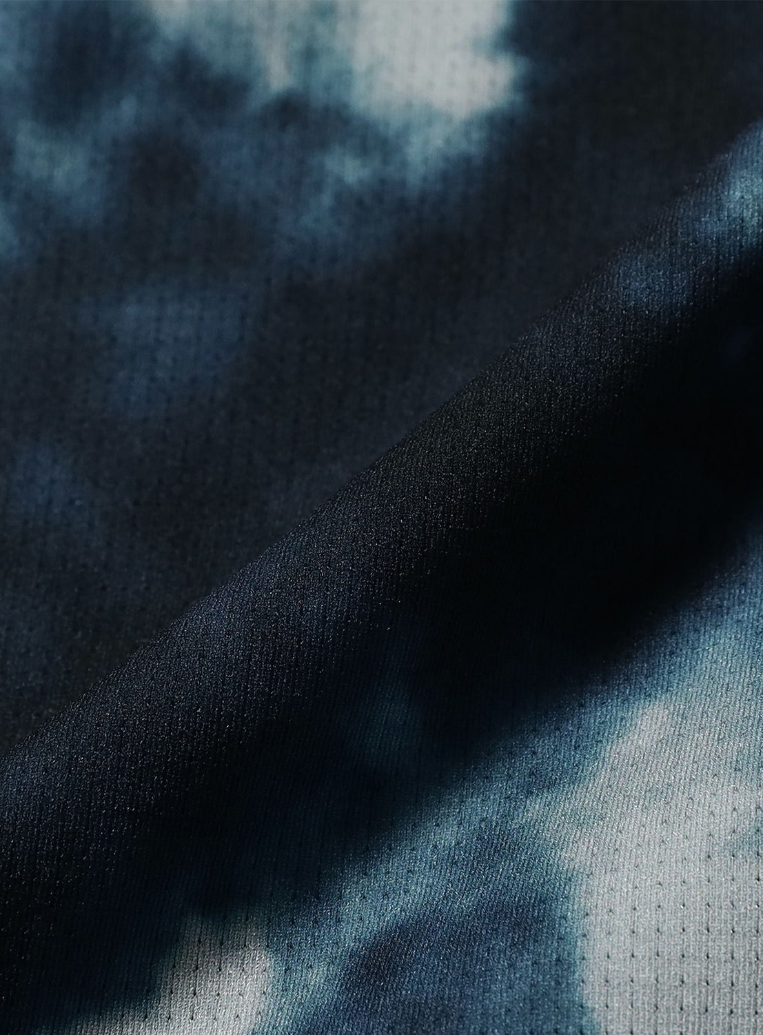 A close-up of fabric with a dark blue and white tie-dye pattern, highlighting the texture and weave found in BEAMS’ Wide Straight Fit Dynamic Dry Easy Pants.