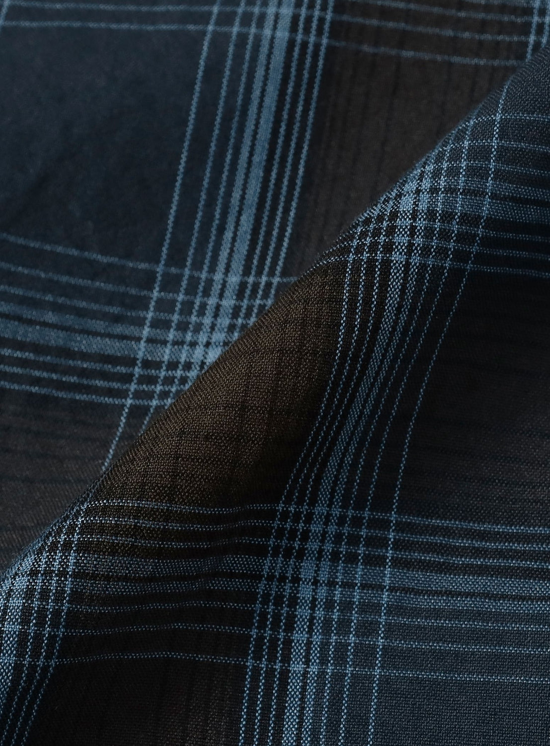 Close-up of dark blue plaid fabric with a visible brand label.