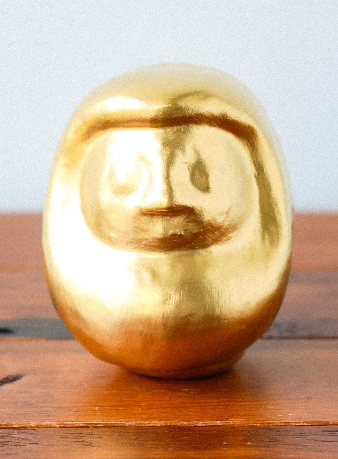 Gold-colored sphere on a wooden surface with a neutral background