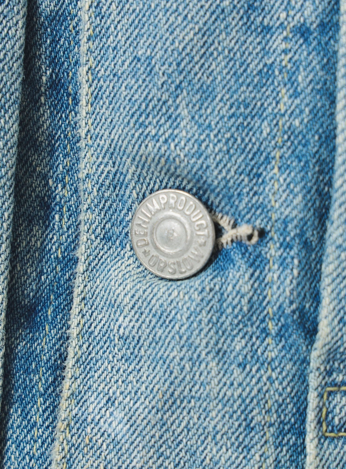 Close-up of a button on blue denim fabric