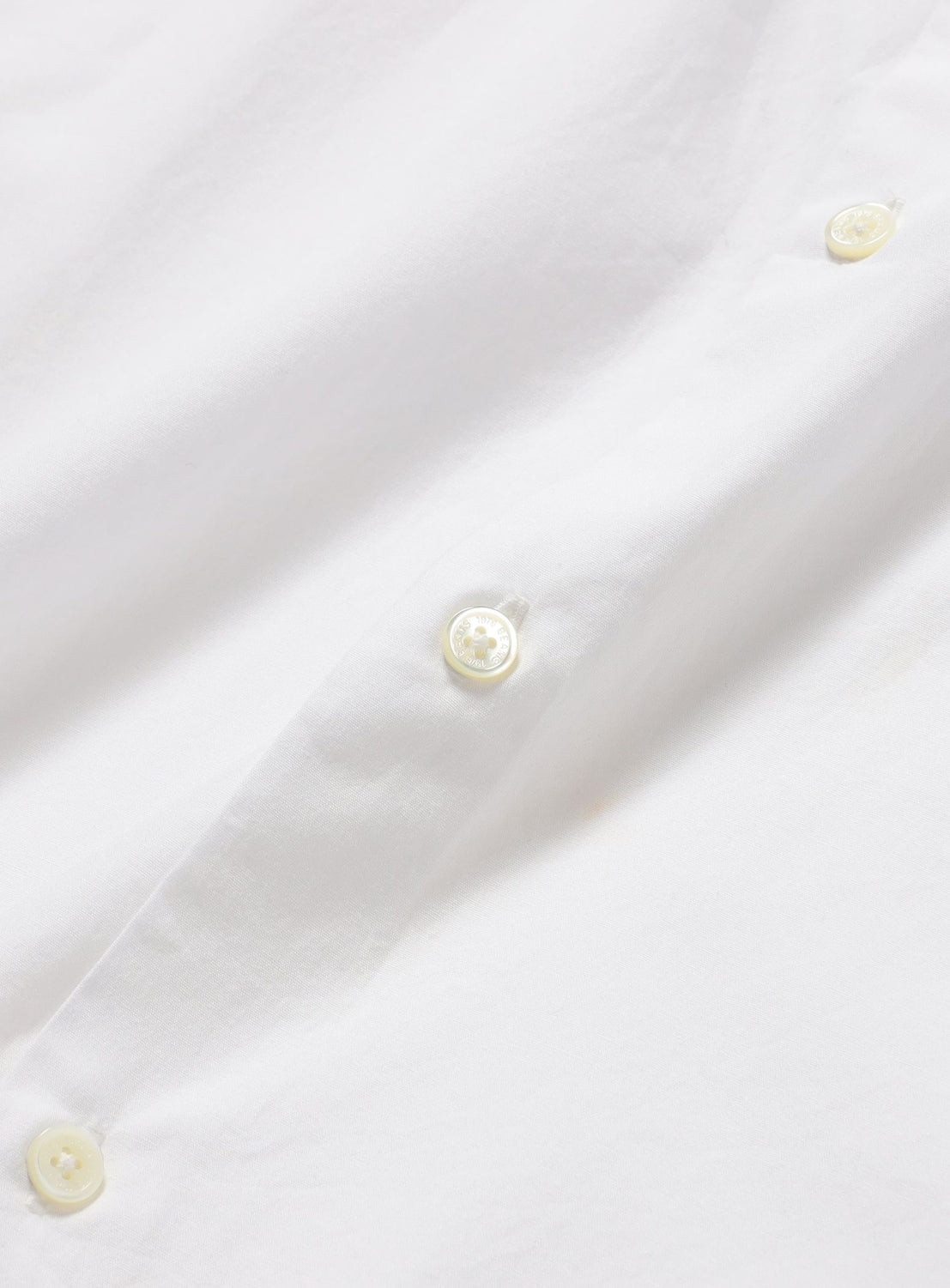 Close-up of a white BEAMS Broadcloth Shirt featuring a vertical placket with three light-colored buttons.