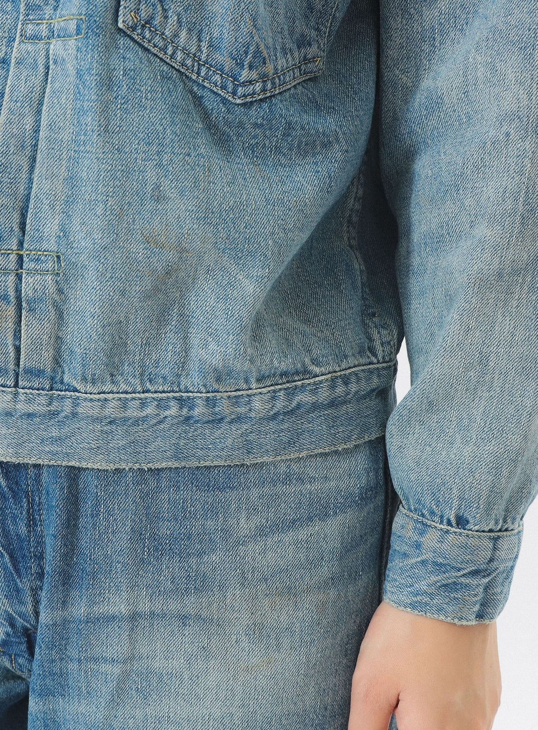Close-up of a person wearing a blue denim jacket and pants on a white background