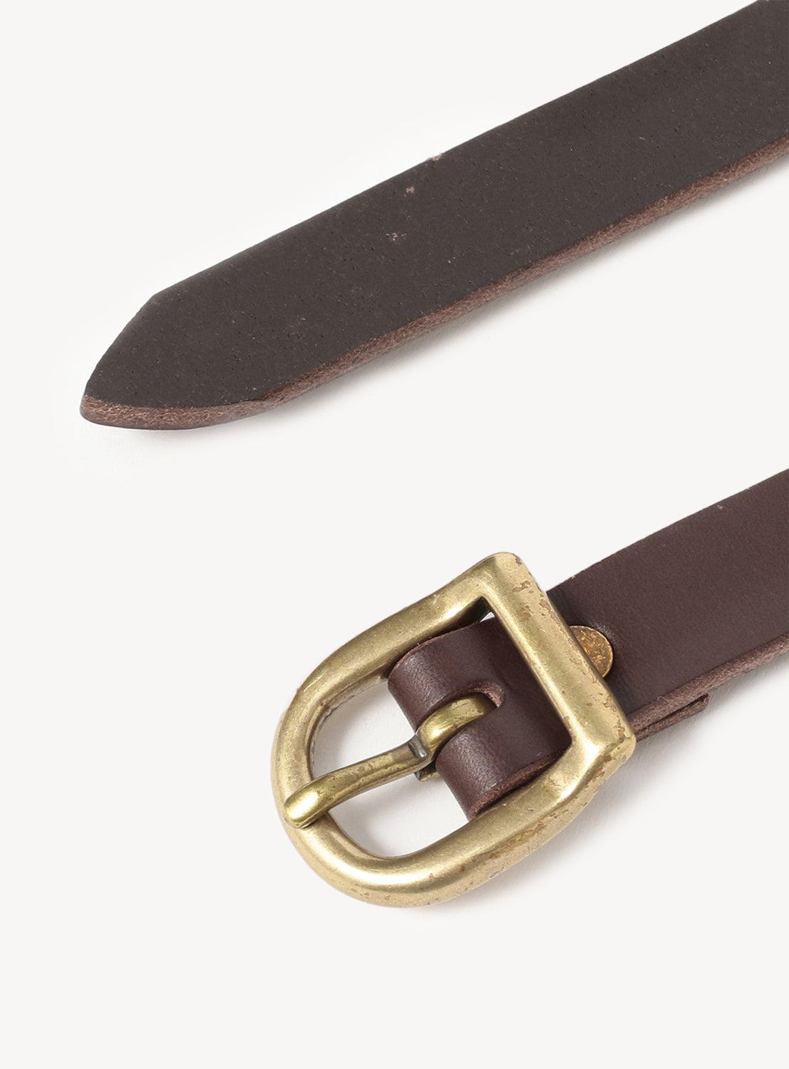 A close-up of the Hender Scheme Arc Belt, featuring a slim genuine leather strap and a curved oval brass buckle. Pointed tip design shown on a white background for lasting style.