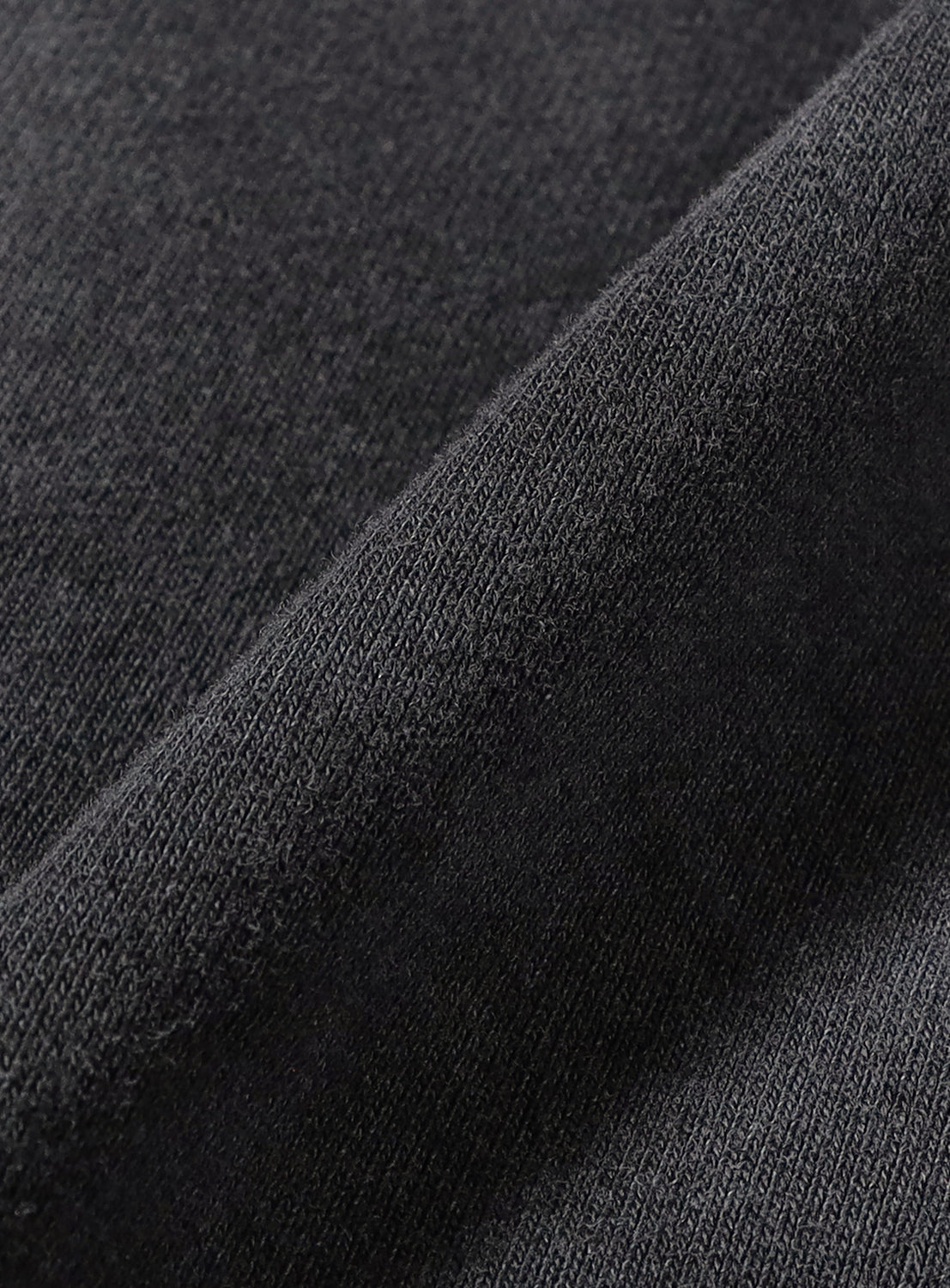A close-up of a vintage-inspired dark grey BEAMS Faded Souvenir Half Zip Pullover, showing a folded edge and the knit texture of the cropped silhouette.