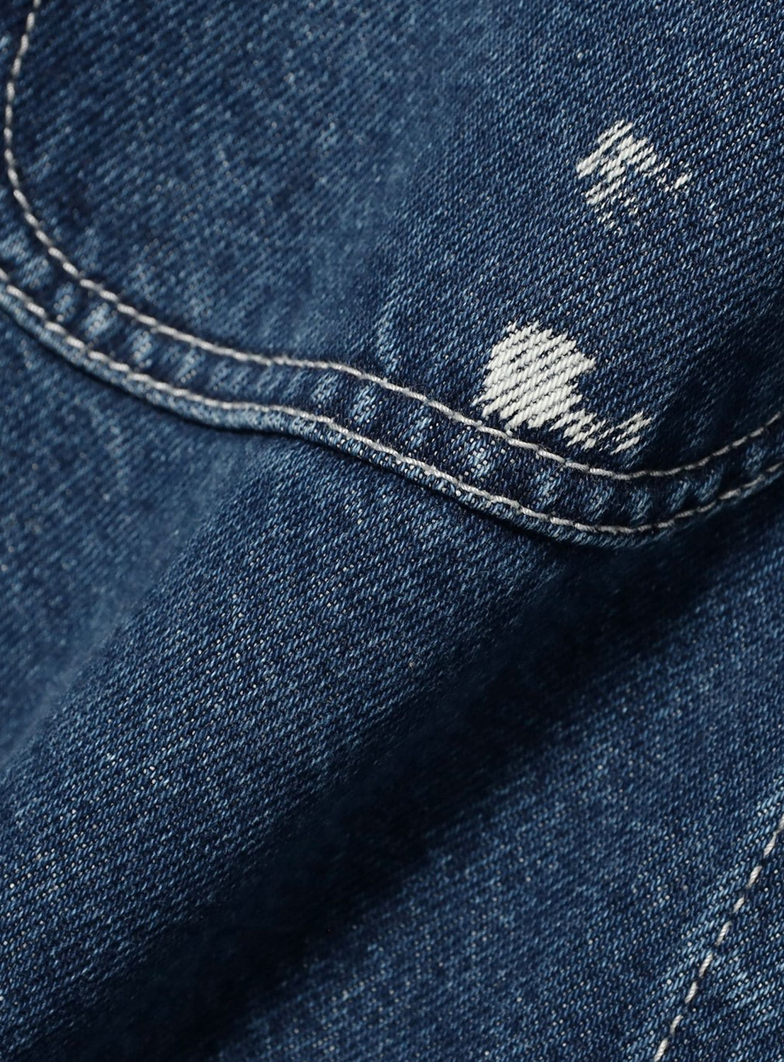 Close-up of a BEAMS Used Denim Coverall in relaxed-fit blue fabric, featuring visible contrast stitching and white distressed spots characteristic of vintage denim.