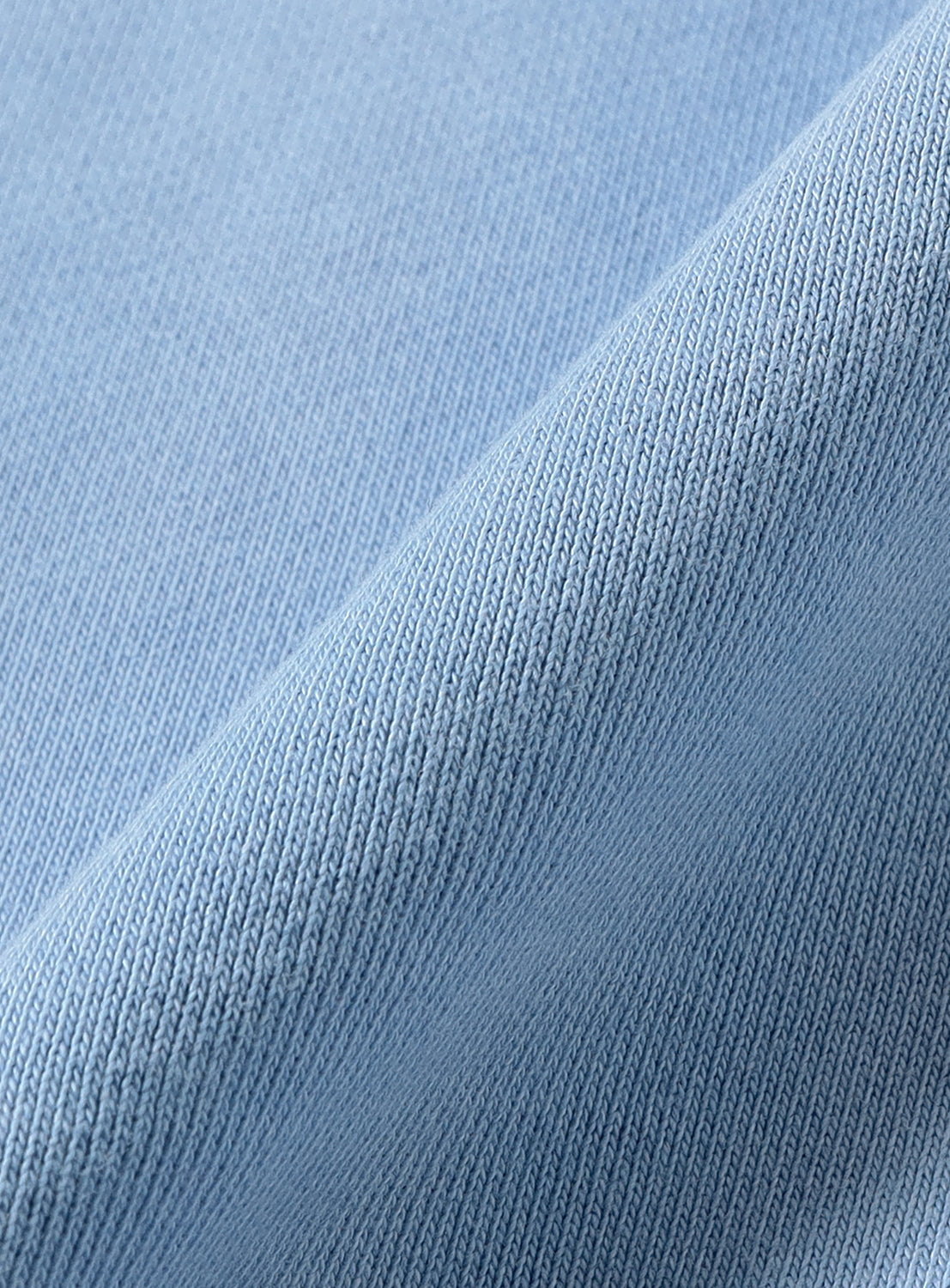 Close-up of the light blue cotton knit fabric of a Faded Souvenir Half Zip Pullover, folded to show the texture of this vintage-inspired half-zip sweatshirt.
