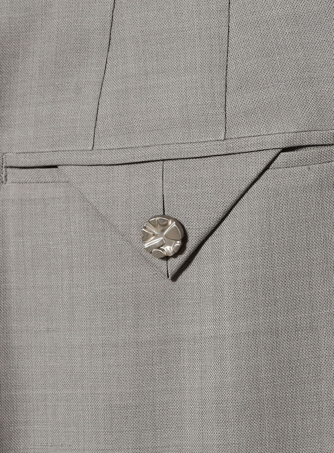 Close-up of KANAKO SAKAI Sheer Trousers in light gray, showcasing a tailored pocket with a triangular flap and decorative silver button.