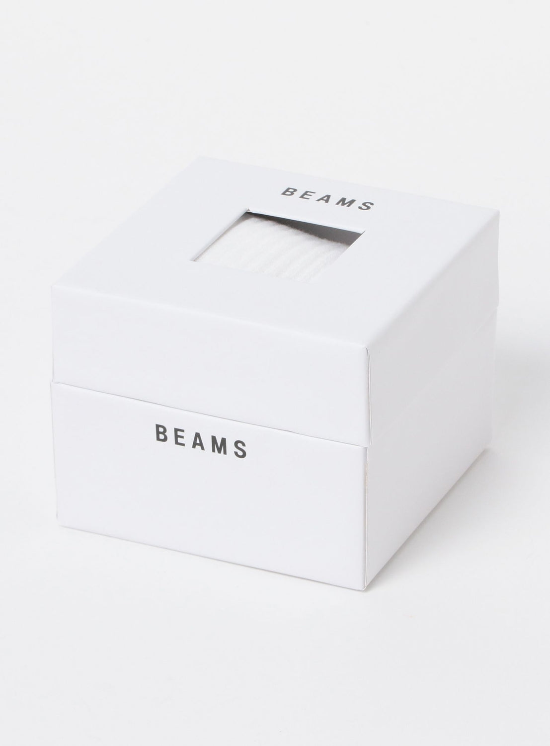 White cardboard box for BEAMS New Basic Socks with a square cutout on the lid revealing the white, ribbed socks inside.