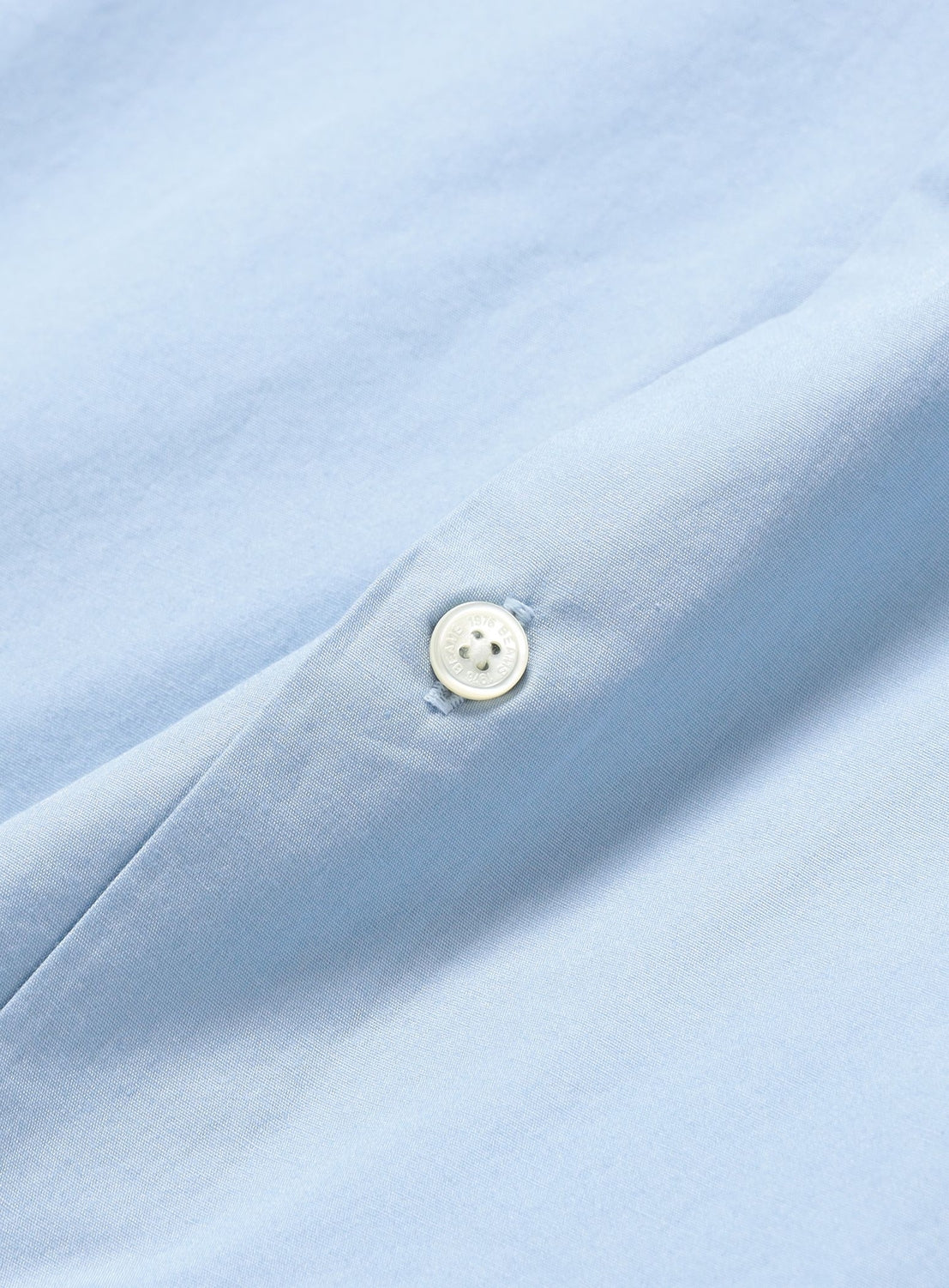Close-up of a light blue BEAMS Broadcloth Shirt, a button-down featuring a single white button centered on the placket.