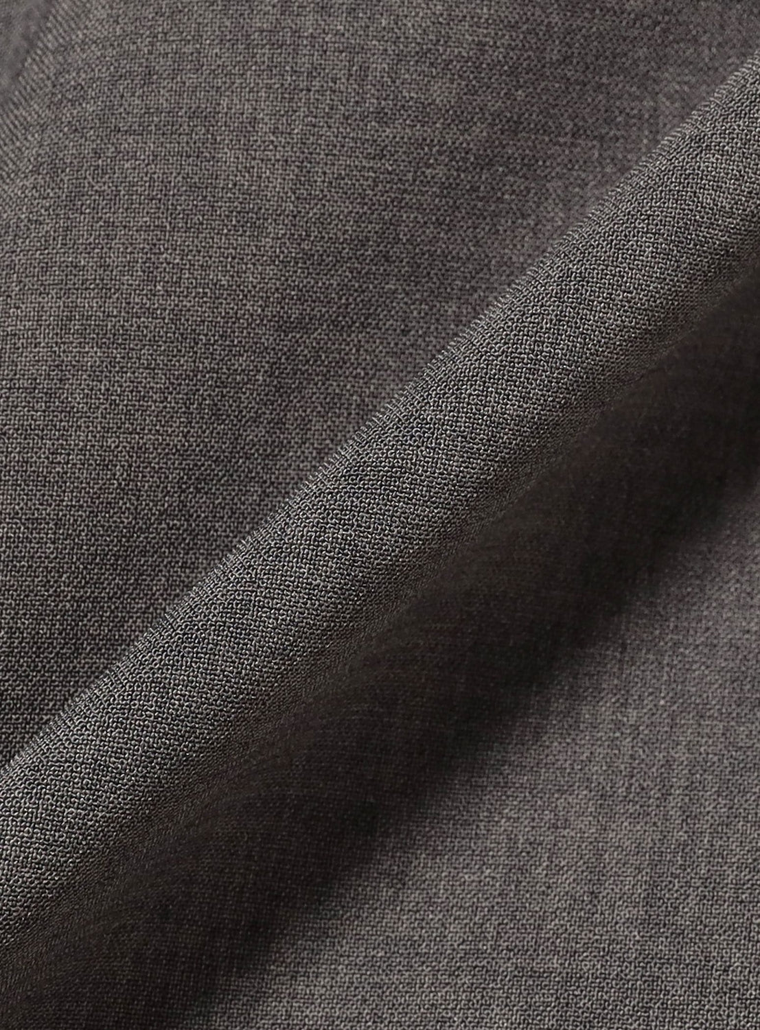 Close-up of gray fabric with a smooth, fine texture and diagonal fold, reflecting the refined look of BEAMS Quick-Dry 2-Pleat Wide Tapered Easy Pants and highlighting their soft, elegant, and moisture-wicking appeal.