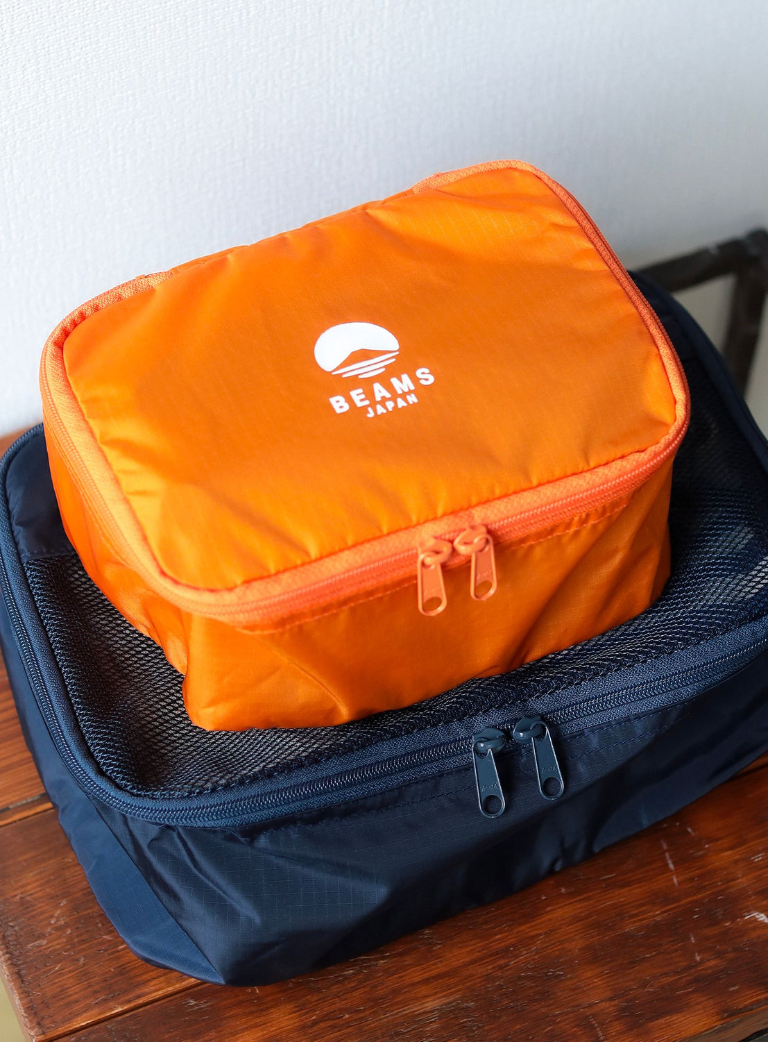 Orange packing cube with a brand logo on top of a blue suitcase.