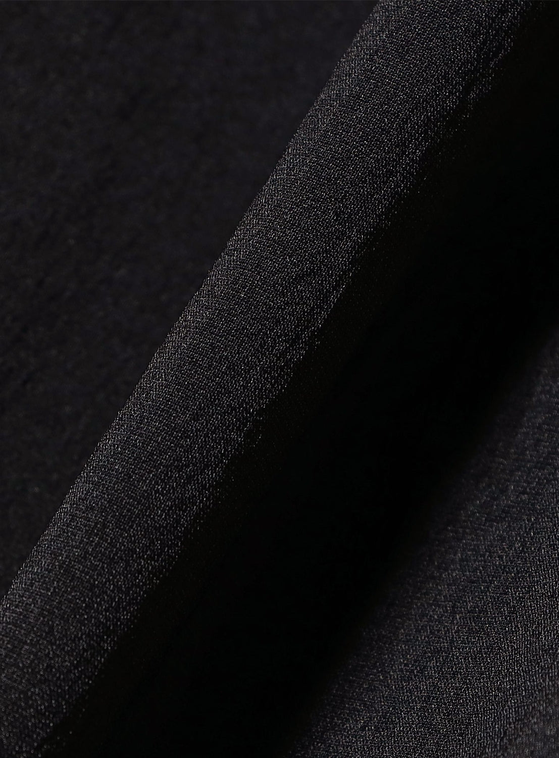 Close-up of a folded piece of dark black DOCTOROID fabric from TEATORA’s Wallet Pants Resort, with visible texture and weave—the interplay of shadows and highlights along the fold showcases its versatility for crafting stylish travel essentials.