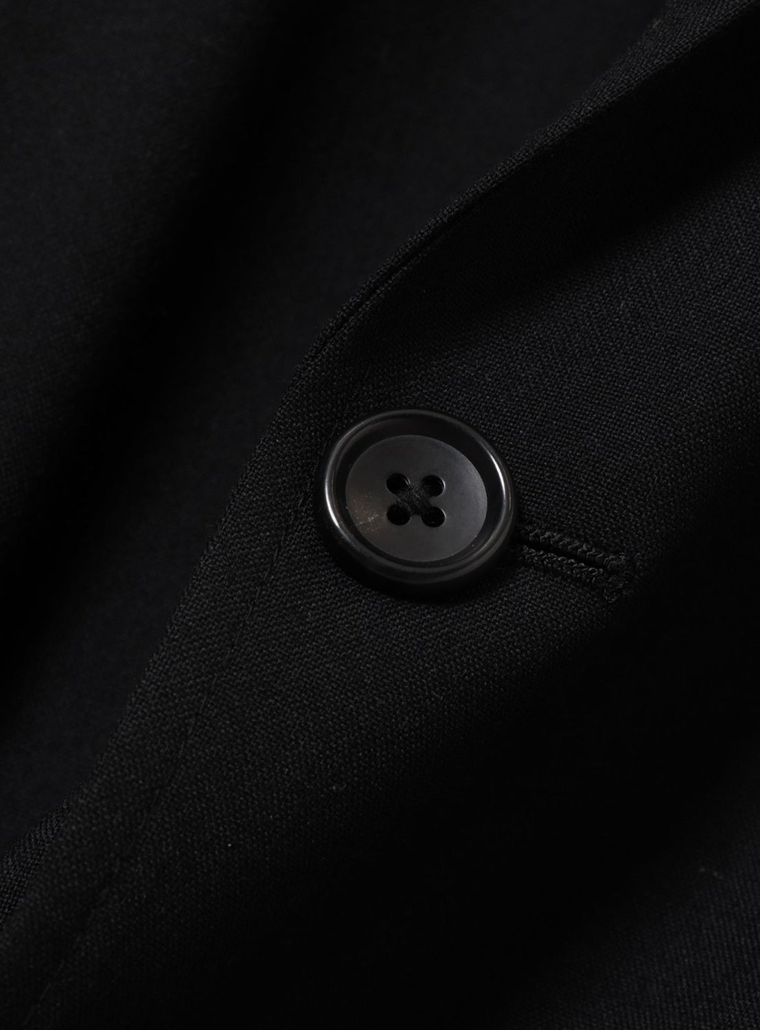 Close-up of a BEAMS Renewool Jacket in a relaxed, wrinkle-resistant black fabric featuring a single centered button.