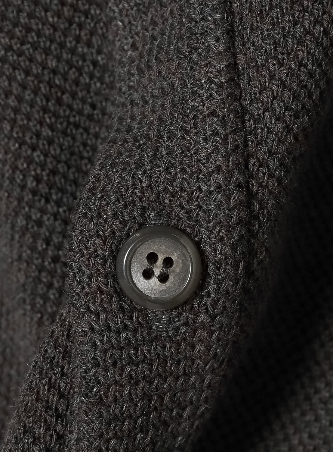 Close-up of a textured dark gray fabric with a button.