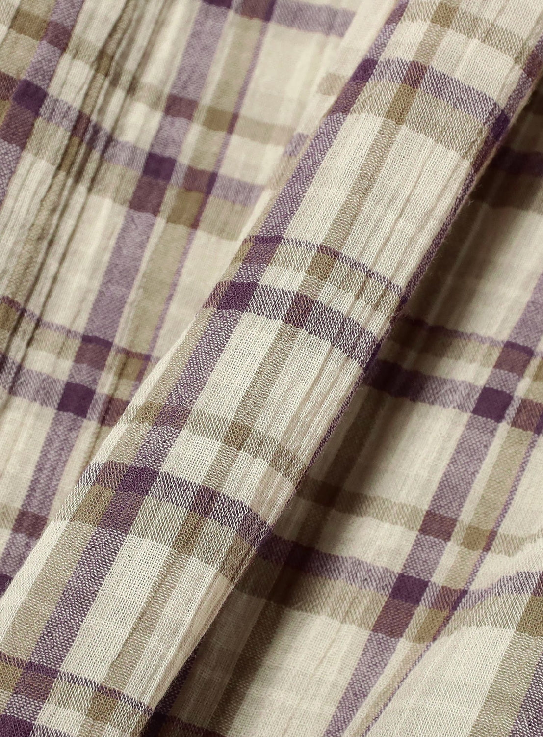 A close-up of the Check Tiered Skirt by BEAMS BOY, crafted from beige lightweight fabric with a plaid pattern featuring intersecting purple and olive green lines—reminiscent of the brand’s signature check design—and highlighting the texture and folds of the material.