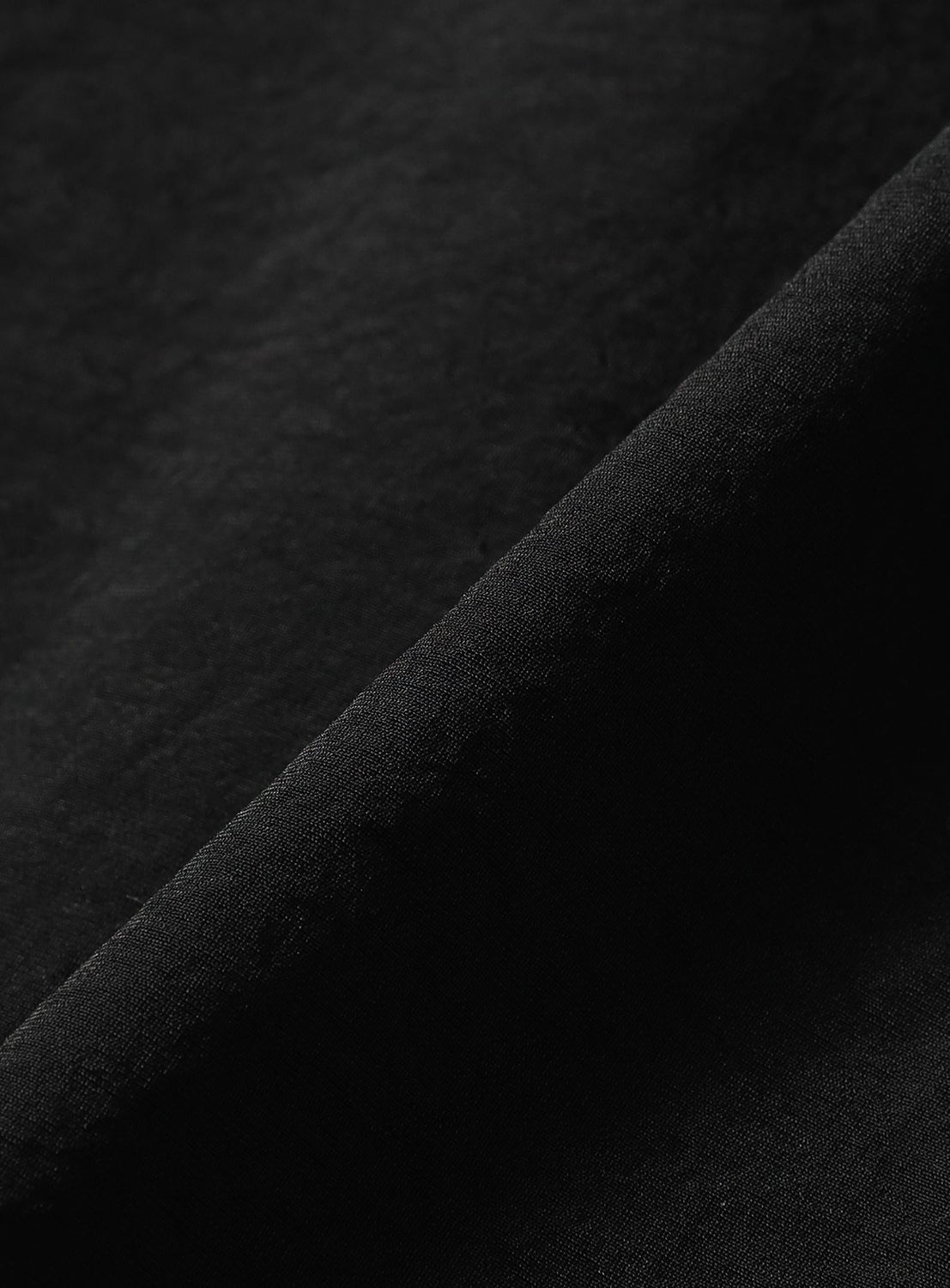 A close-up of TEATORA’s AQ Short Sleeve Cartridge Shirt in black, featuring wrinkle-resistant, quick-drying fabric with a smooth texture and subtle tonal variations—perfectly suited for travel.
