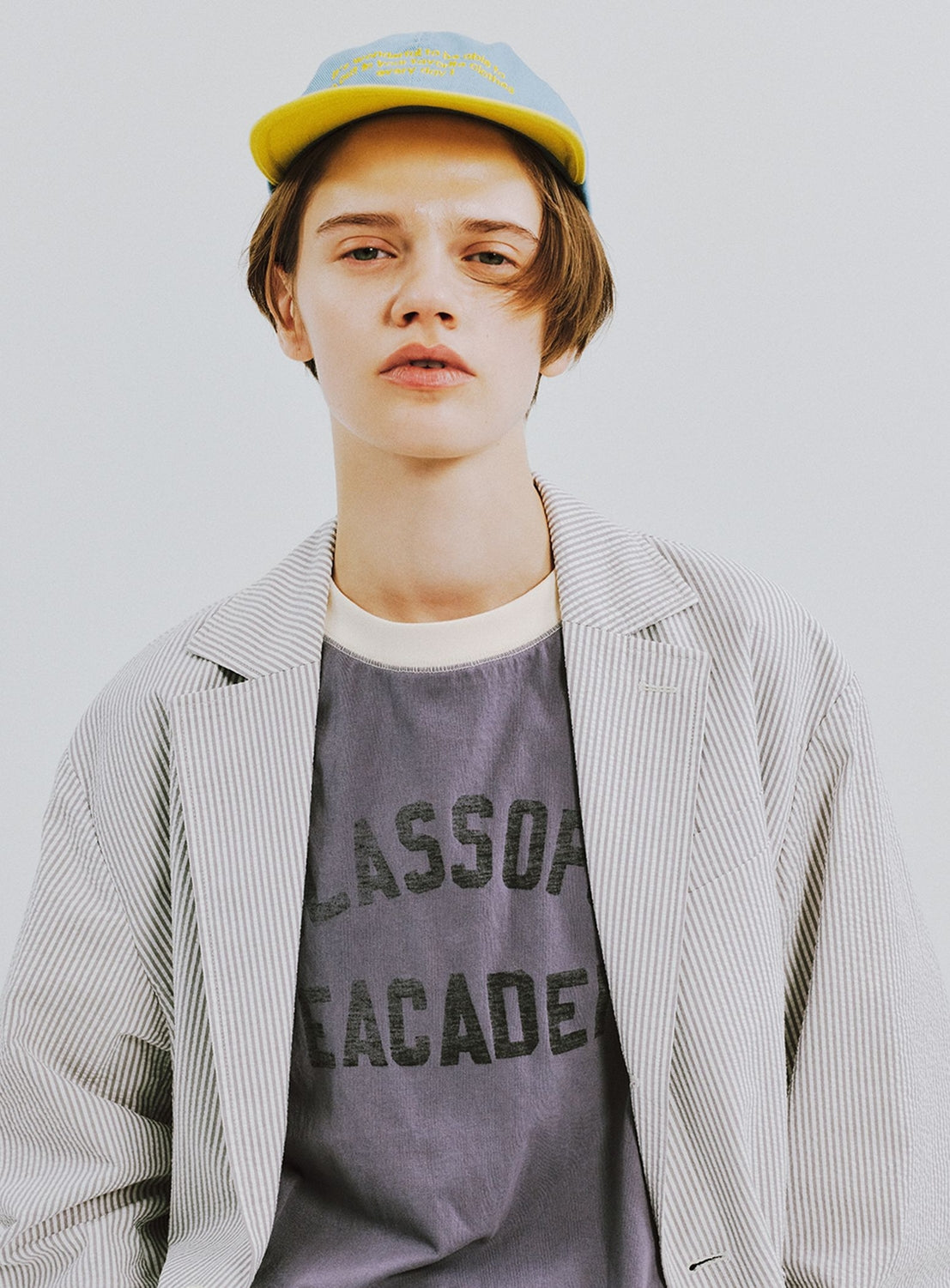 A person in a yellow cap, striped blazer, and BEAMS BOY Two-Tone Vintage Raglan T-shirt with partial text poses neutrally against a plain light background.