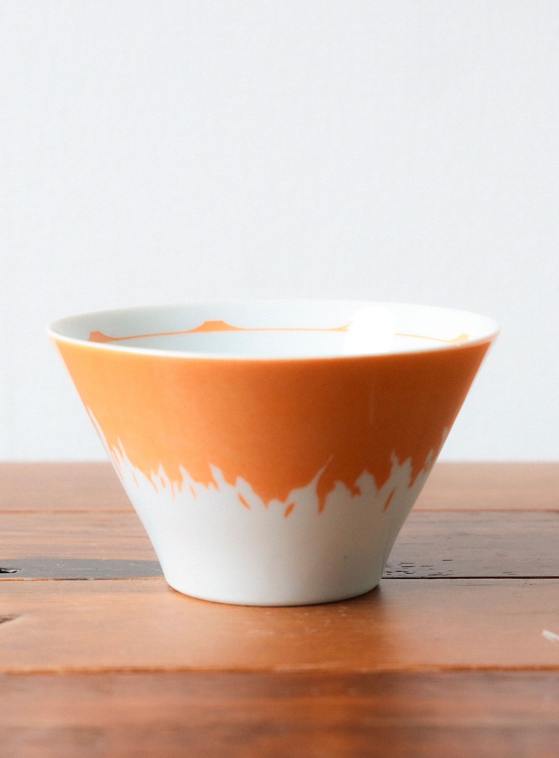 Ceramic bowl with orange and white design on a wooden surface