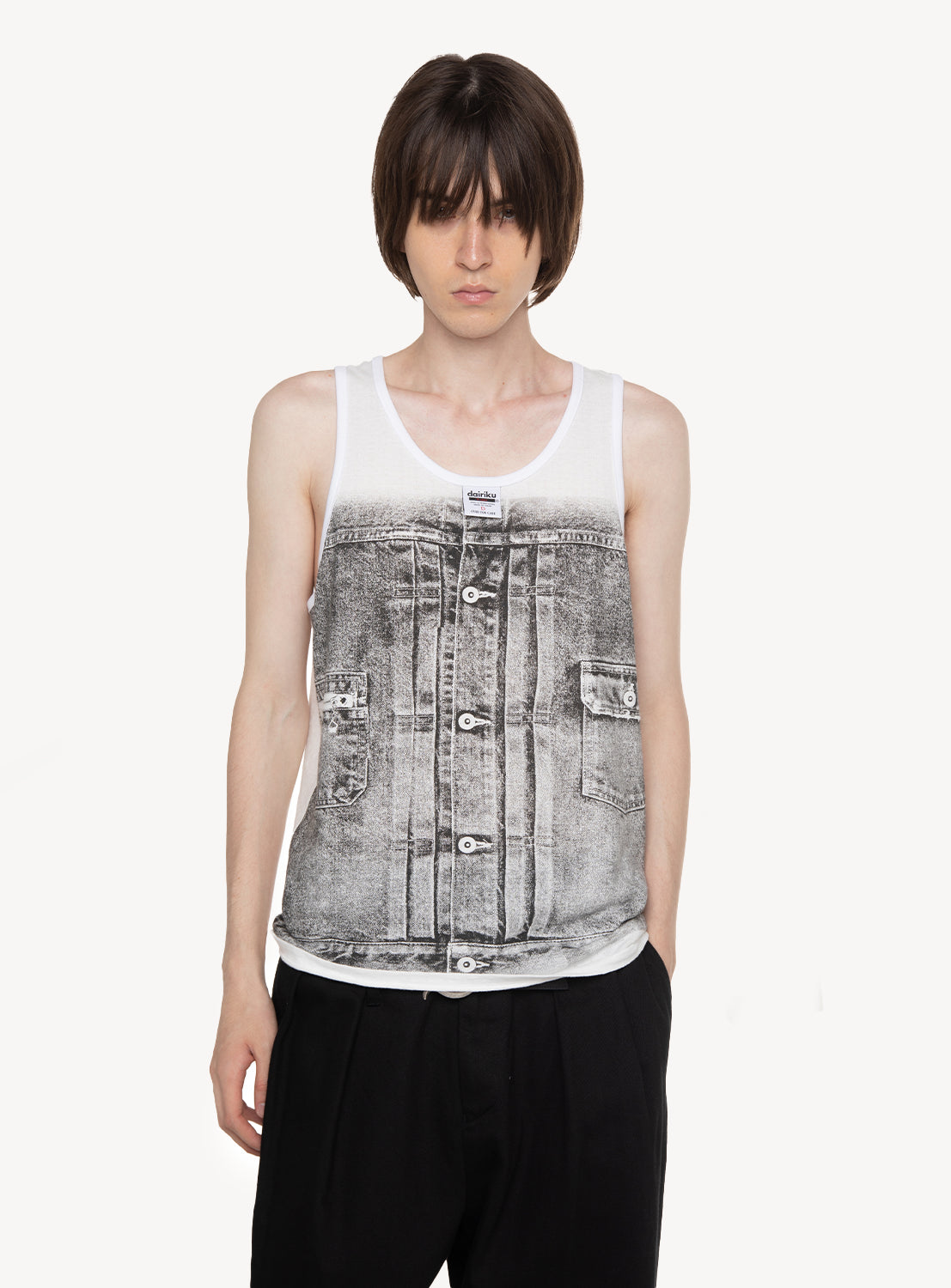 A person wearing the DAIRIKU "Matt" Transfer Print Fancy Dobby Tag Tank Top, featuring a realistic trompe-l'œil denim jacket print over a white base, paired with black pants and standing against a plain white background.