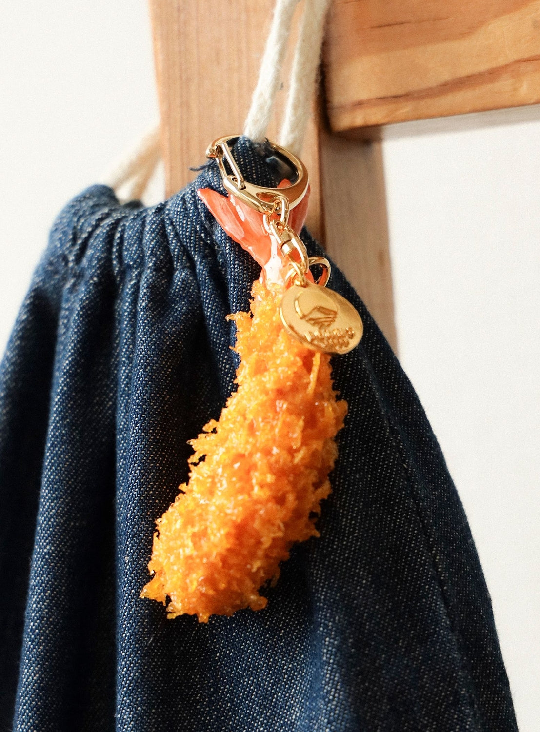Orange textured keychain with a gold tag attached to a dark blue fabric background.
