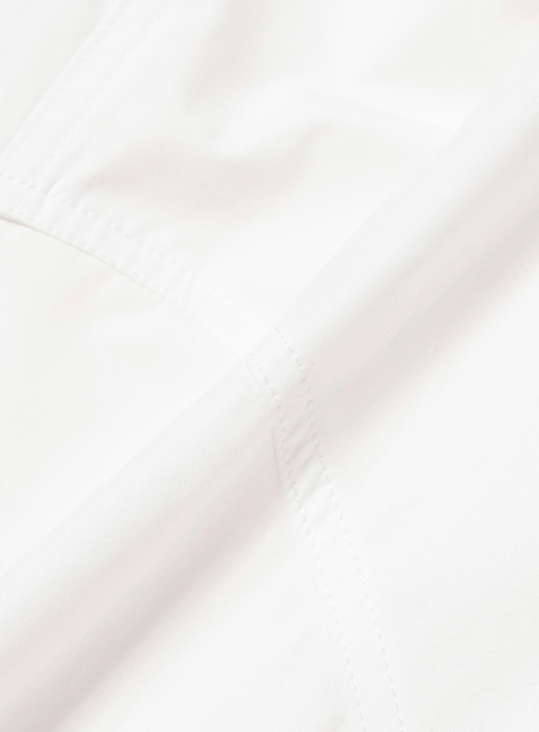 Close-up of the Naleen Cotton Dress by HARUNOBUMURATA, showcasing white fabric with visible stitching and subtle folds.