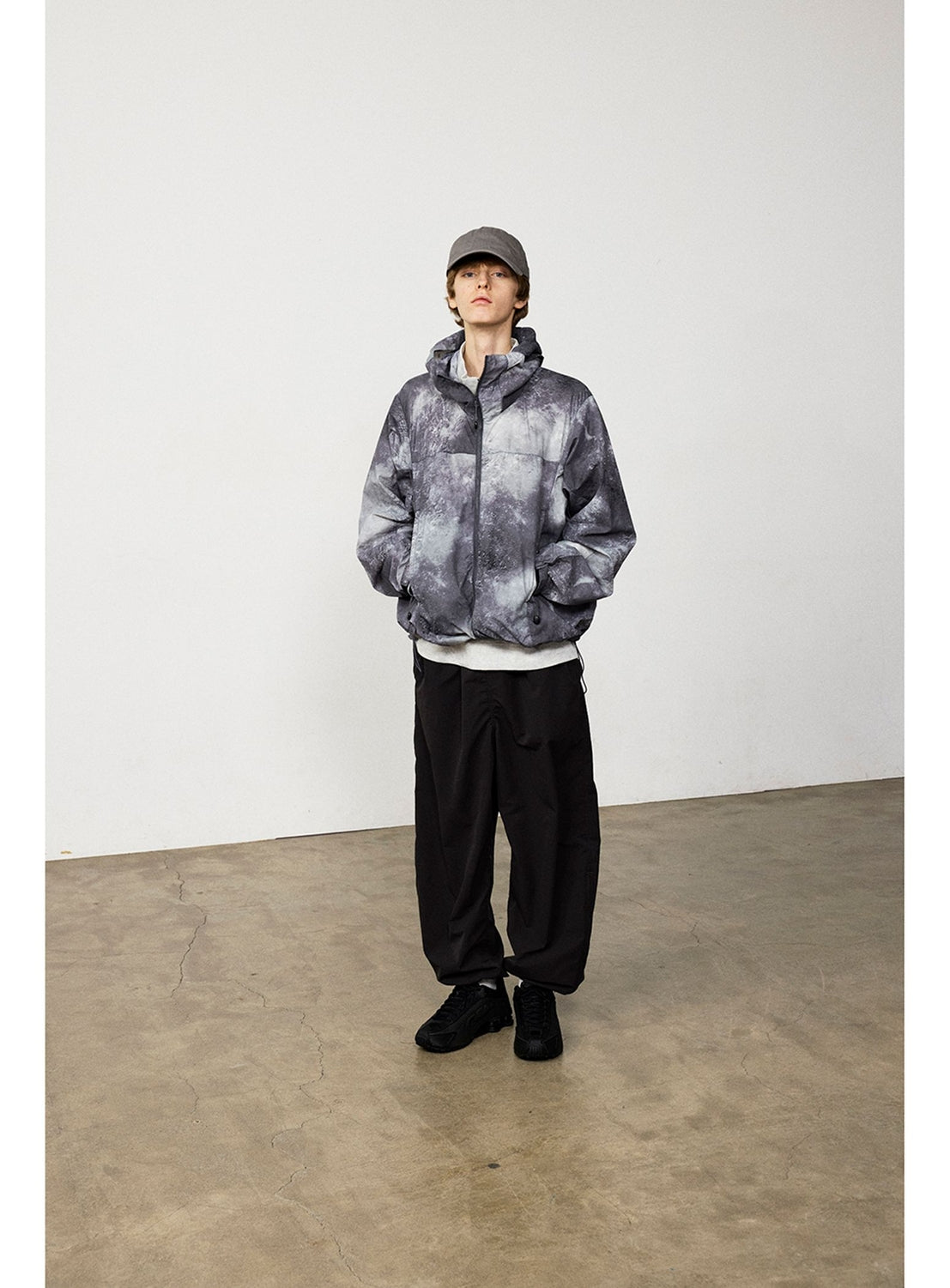 A person wearing a grey tie-dye print zip-up jacket, a white shirt, BEAMS Technical 2-Way Adjustable Easy Pants, and a baseball cap.