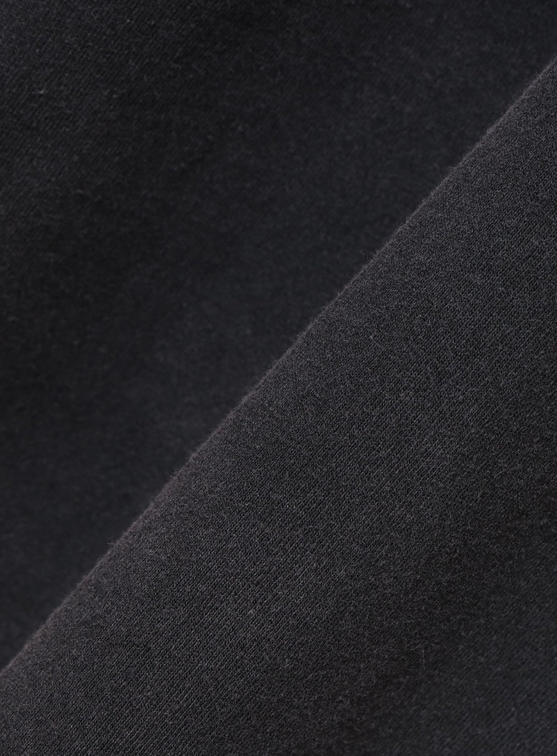 Two different textures of black fabric stacked on top of each other.