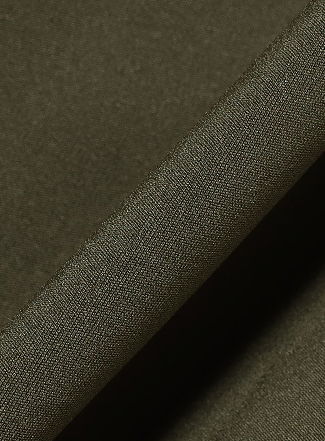 Close-up of olive green fabric with a fine, smooth weave—characteristic of the TTT MSW 5-Pocket Jersey Pants—shown with a visible fold diagonally across the image.