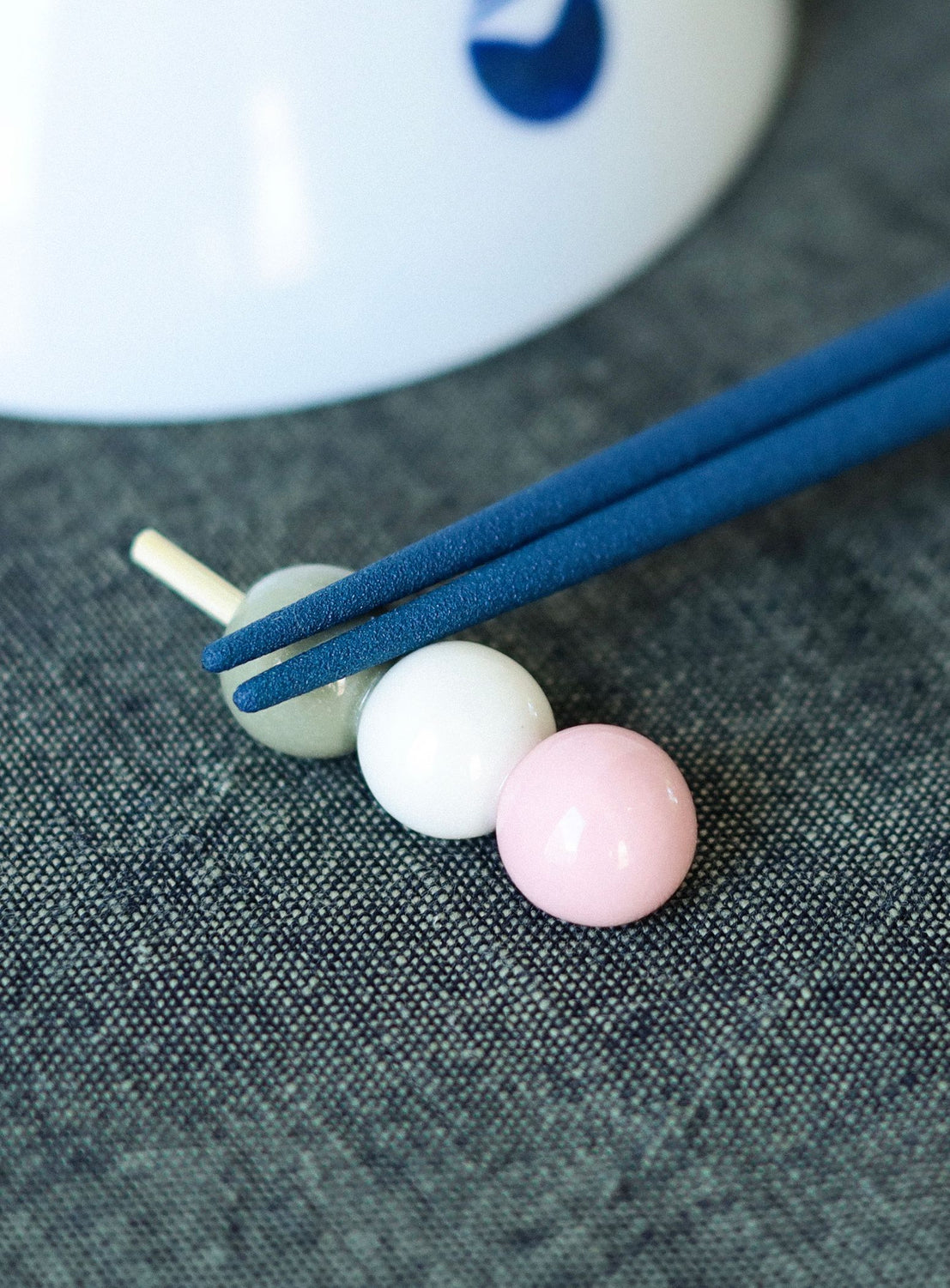 Blue chopsticks on food hopstick rest on a textured gray surface.