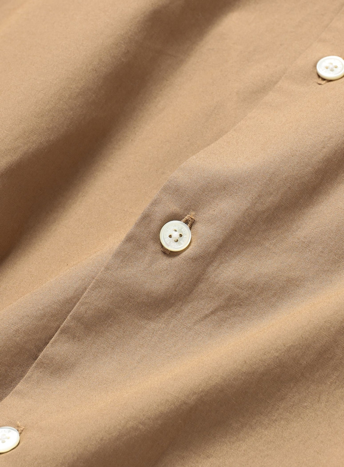 Close-up of a tan BEAMS Broadcloth Shirt featuring light-colored buttons and a regular collar.