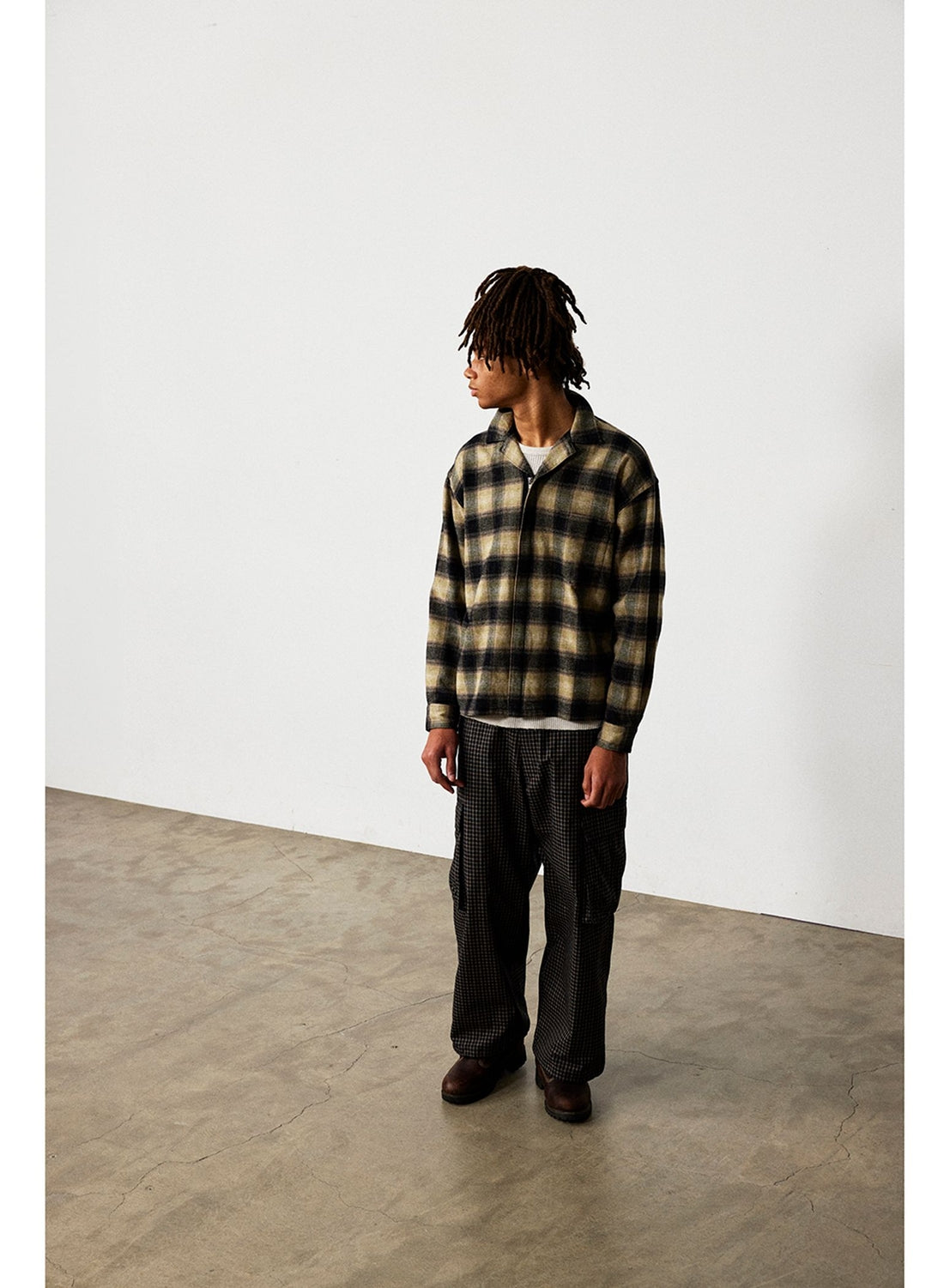 Person wearing a tan and black check pattern BEAMS Flannel Zip Open Collar Shirt over a white t-shirt and dark patterned trousers.